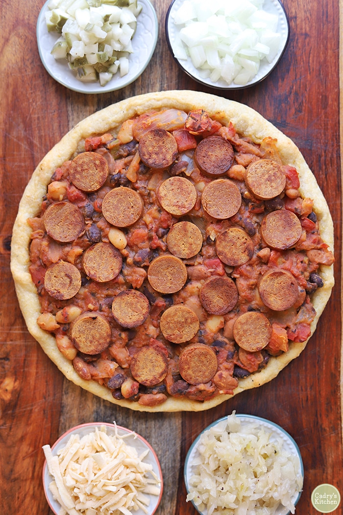 Overhead chili dog pizza with toppings.