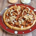 Hot dog pizza with chili on round plate.