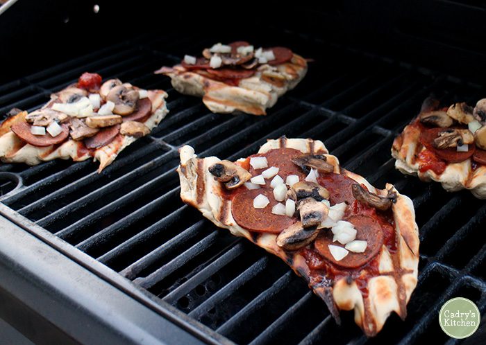 Pizza with vegan pepperoni and mushrooms on grill.