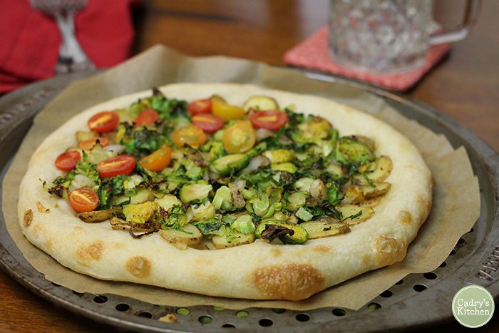 Pizza with Brussels sprouts on parchment paper lined baking sheet.