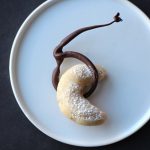 Crescent cookie with chocolate lasso on plate.