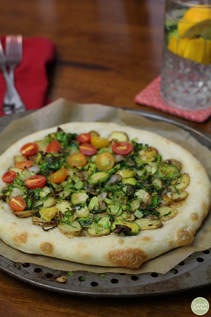 Close-up Brussels sprouts pizza with cherry tomatoes.