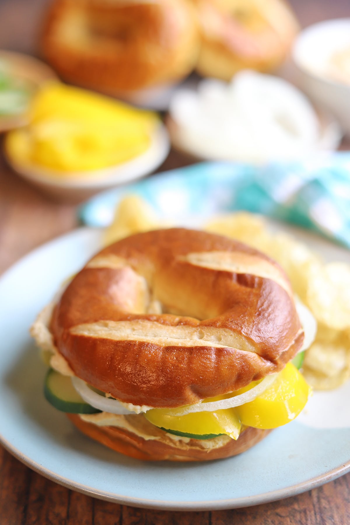 Bagel sandwich on table with potato chips.