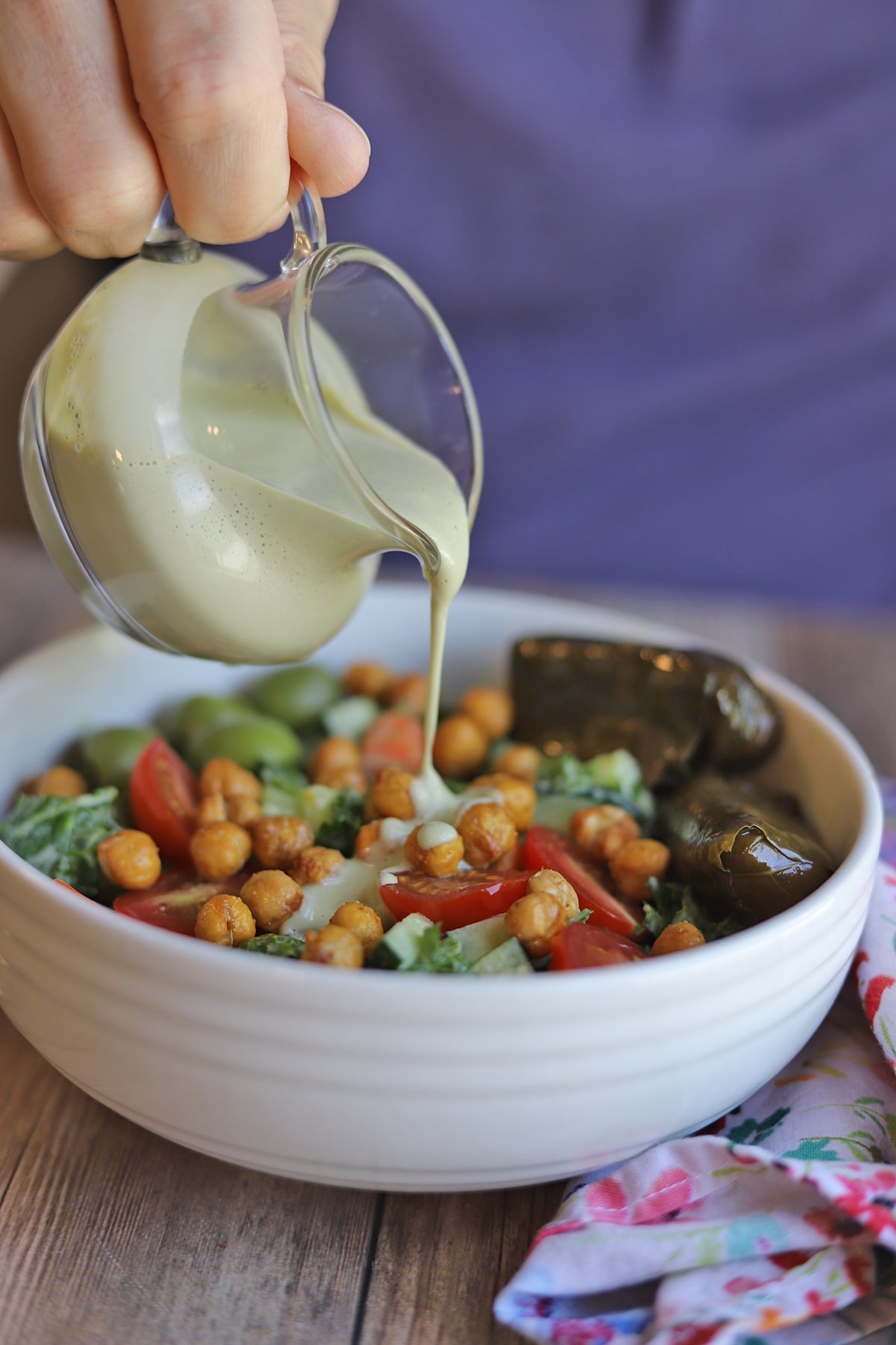 Creamy cashew dressing being poured onto kale salad.
