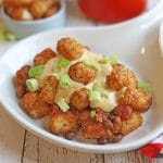 Tater tots on platter with cashew queso and chili.