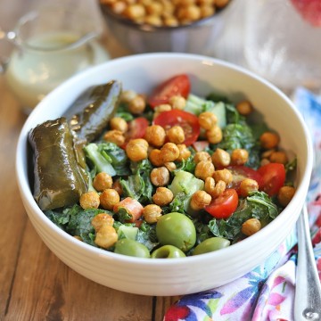 Kale salad in bowl with roasted chickpeas, dolmas, and olives.