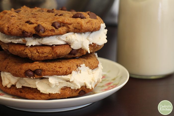 Chocolate chip cookie sandwiches with vanilla frosting on plate.