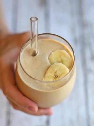 Hand holding smoothie in glass.