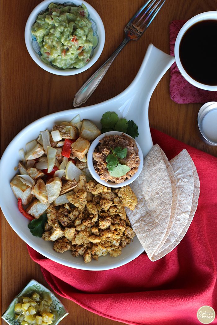 Overhead tofu scramble, refried beans, and guacamole on table.