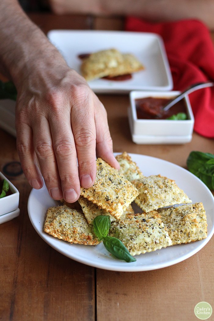 Hand reaching out for a fried ravioli.
