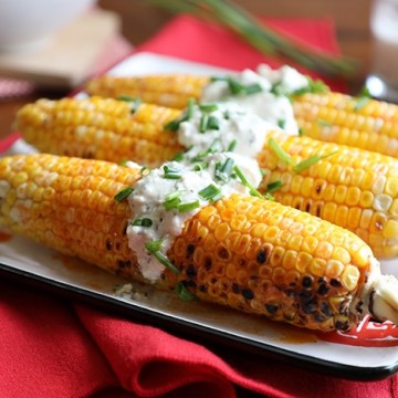 Ears of buffalo-style grilled corn on the cob topped with vegan blue cheese dressing.