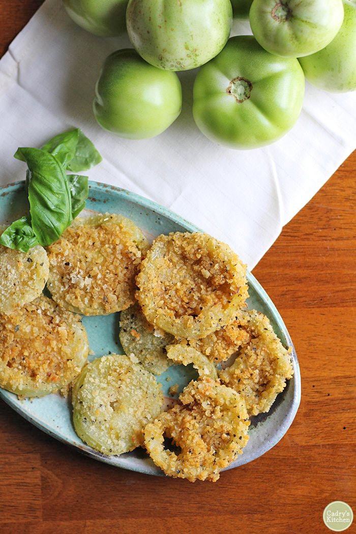 Overhead potato chip crusted green tomatoes on plate with fresh basil.