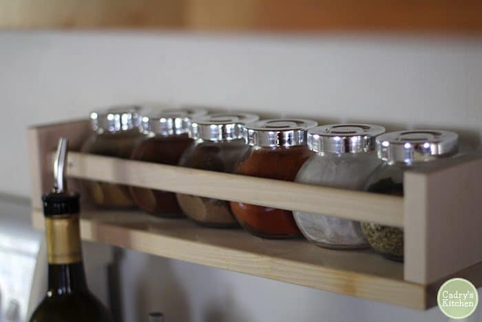 Spice rack holding essential spices for a vegan kitchen - cumin, ancho chili powder, paprika, and more.