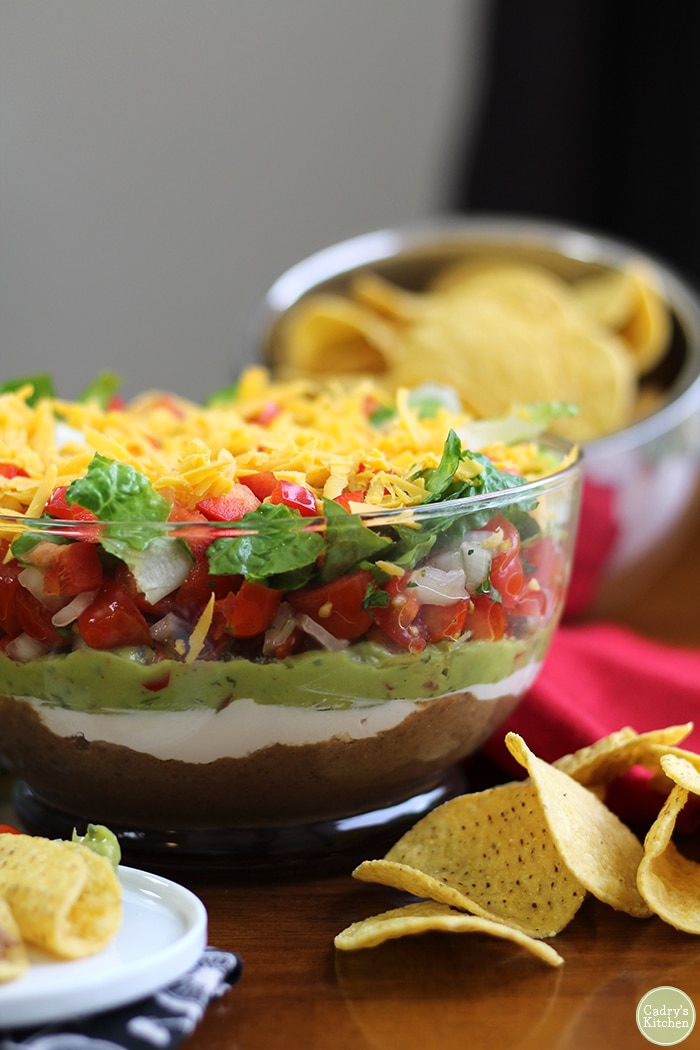 Vegan 7 layer dip in glass bowl with tortilla chips.