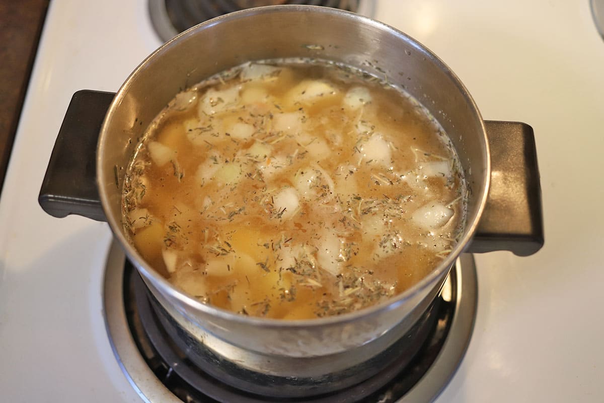 Potatoes, onions, garlic, spices, water, and bouillon in soup pot.