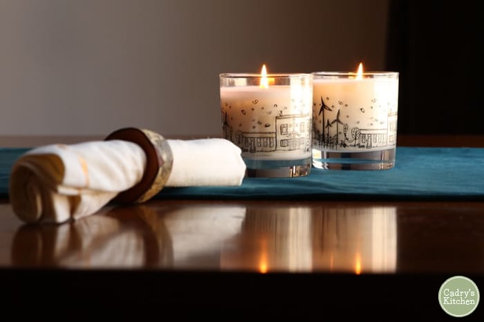Napkin with napkin ring and two candles on table.