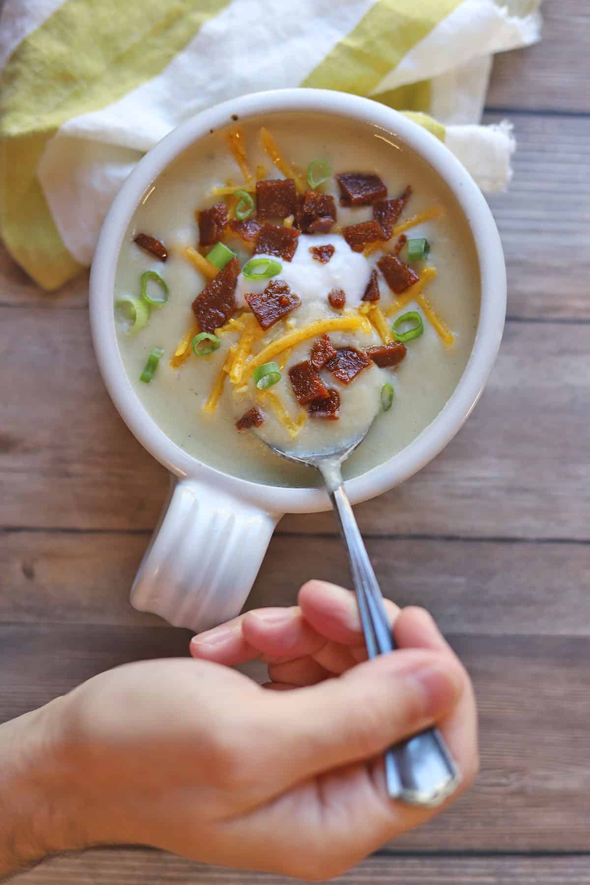 Spoon digging into vegan baked potato soup.