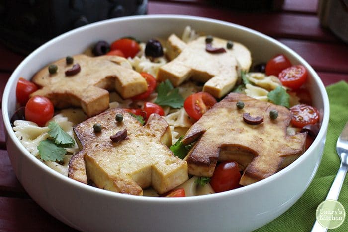Adipose shaped tofu on top of bowtie pasta salad.