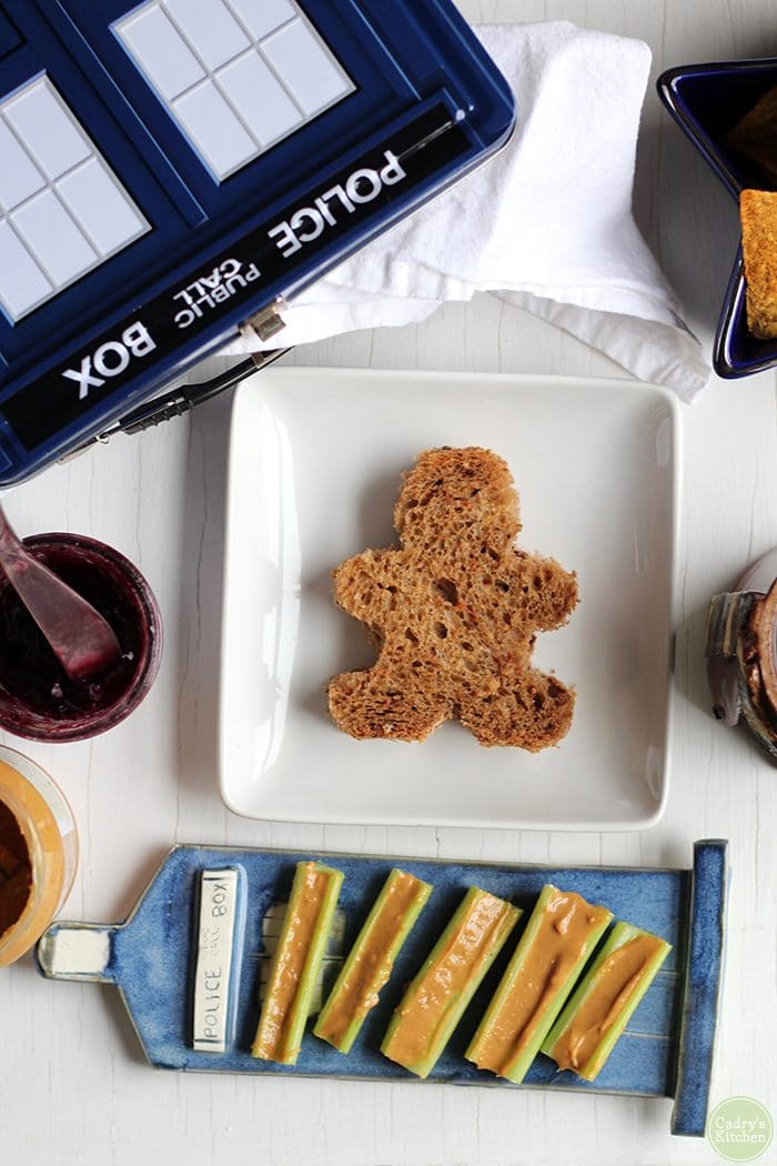 Overhead peanut butter & jelly sandwich, a Doctor Who food idea, with lunchbox and TARDIS plate.