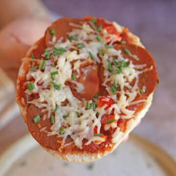 Hand holding pizza bagel.