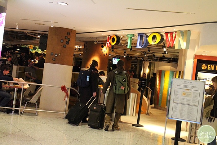 Travelers with suitcase in front of Root Down in the Denver Airport.