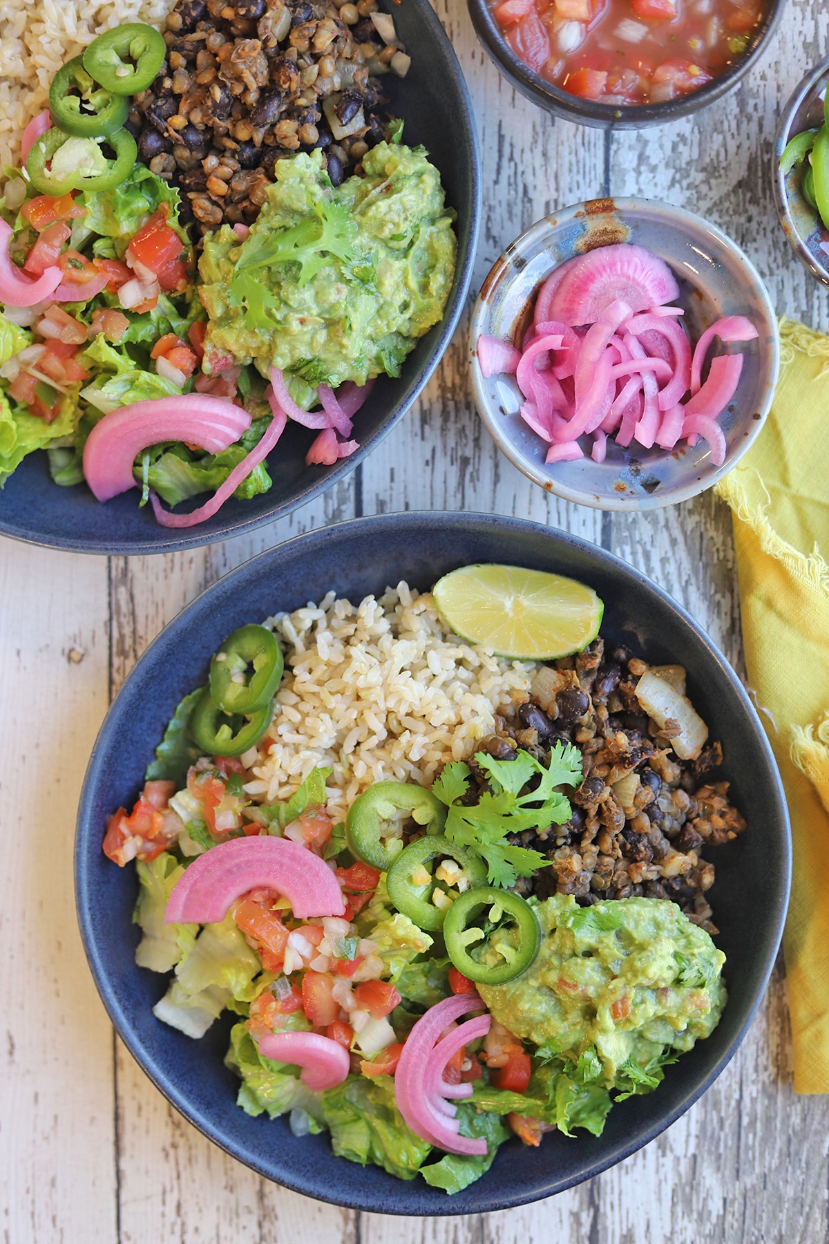 Vegan burrito bowls on table with pickled red onions.