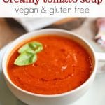 Text overlay: Creamy tomato soup. Vegan and gluten-free. Bowl of soup with fresh basil.
