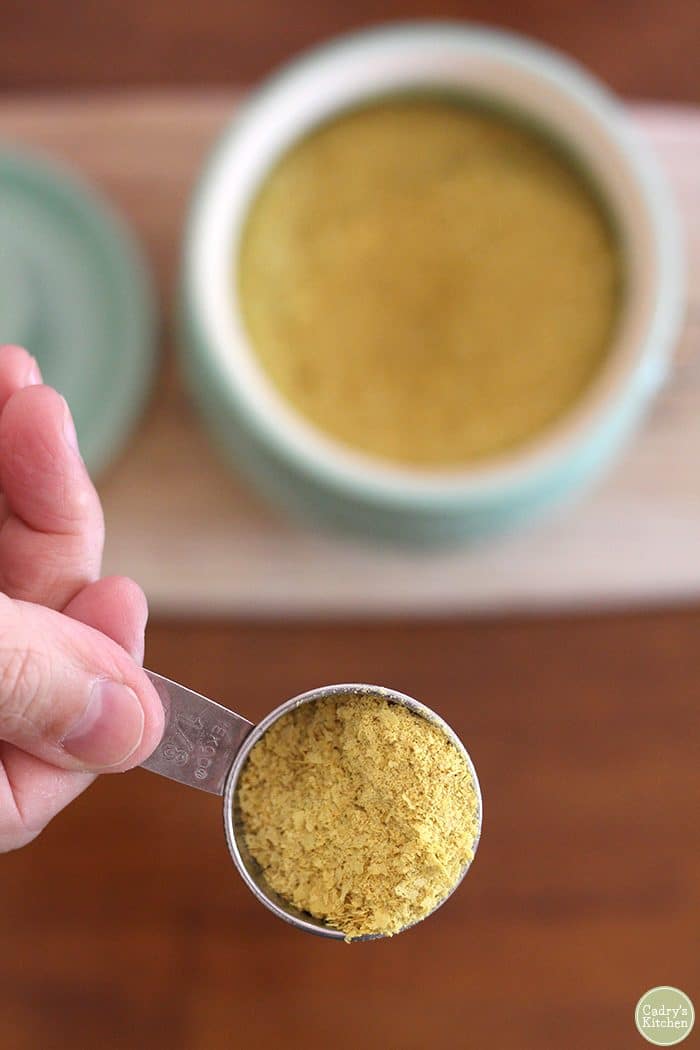 Hand holding nutritional yeast flakes.