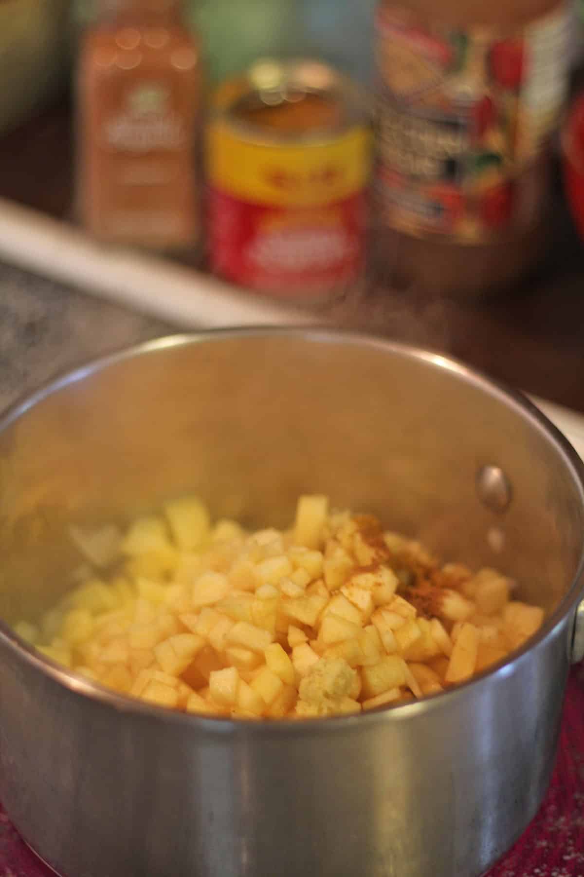 Apples in pot with spices and fresh ginger.
