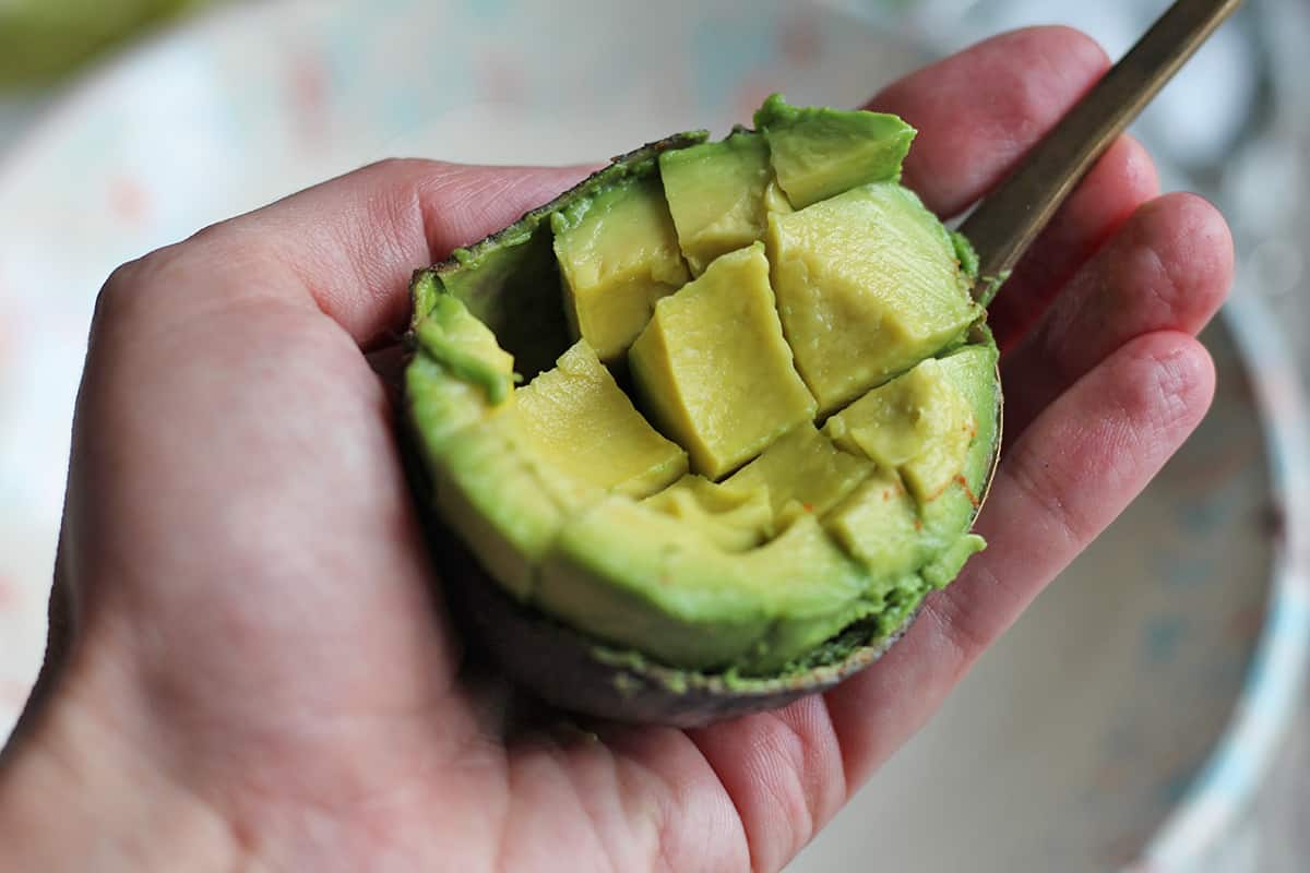 Spoon scooping out avocado flesh from peel.