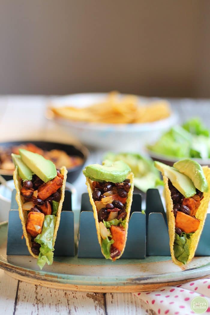 Tacos in taco holders on plate.