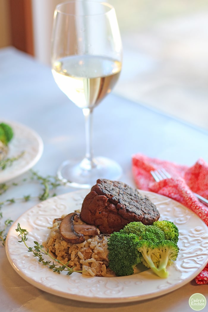 Vegan risotto on plate with seitan steak and steamed broccoli.