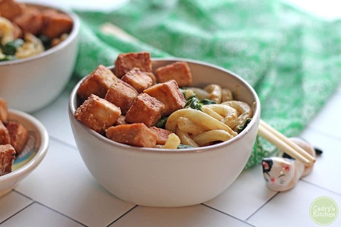 Udon noodles & spinach in bowl with fried cubes of tofu.