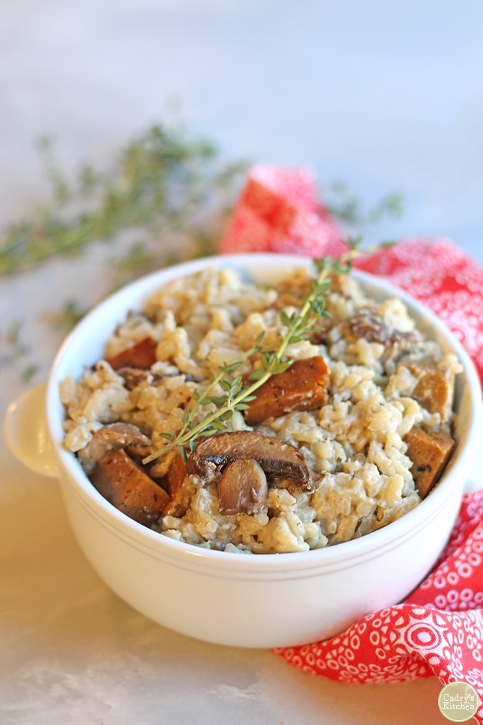 Creamy vegan risotto in bowl with mushrooms and seitan sausage.