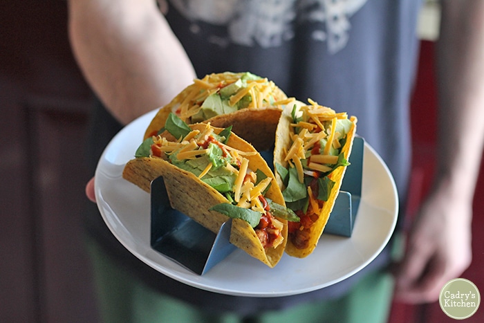 Hand holding chickpea tacos with taco holders.