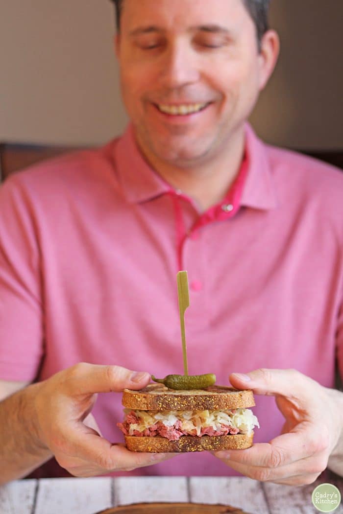 David holding vegan reuben jackfruit sandwich.