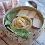 Udon noodle soup with tofu and spinach in bowl.