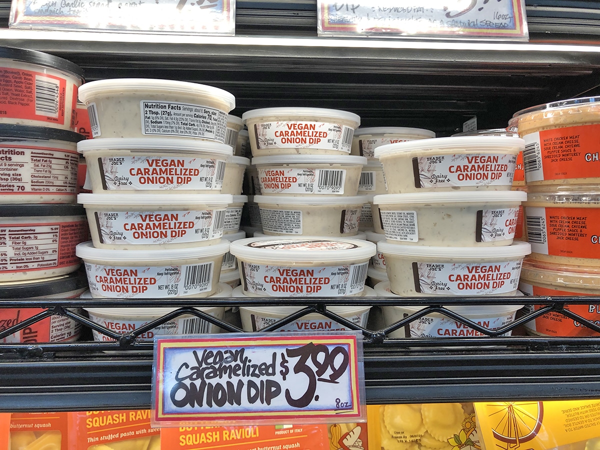 Containers of vegan caramelized onion dip on shelf.