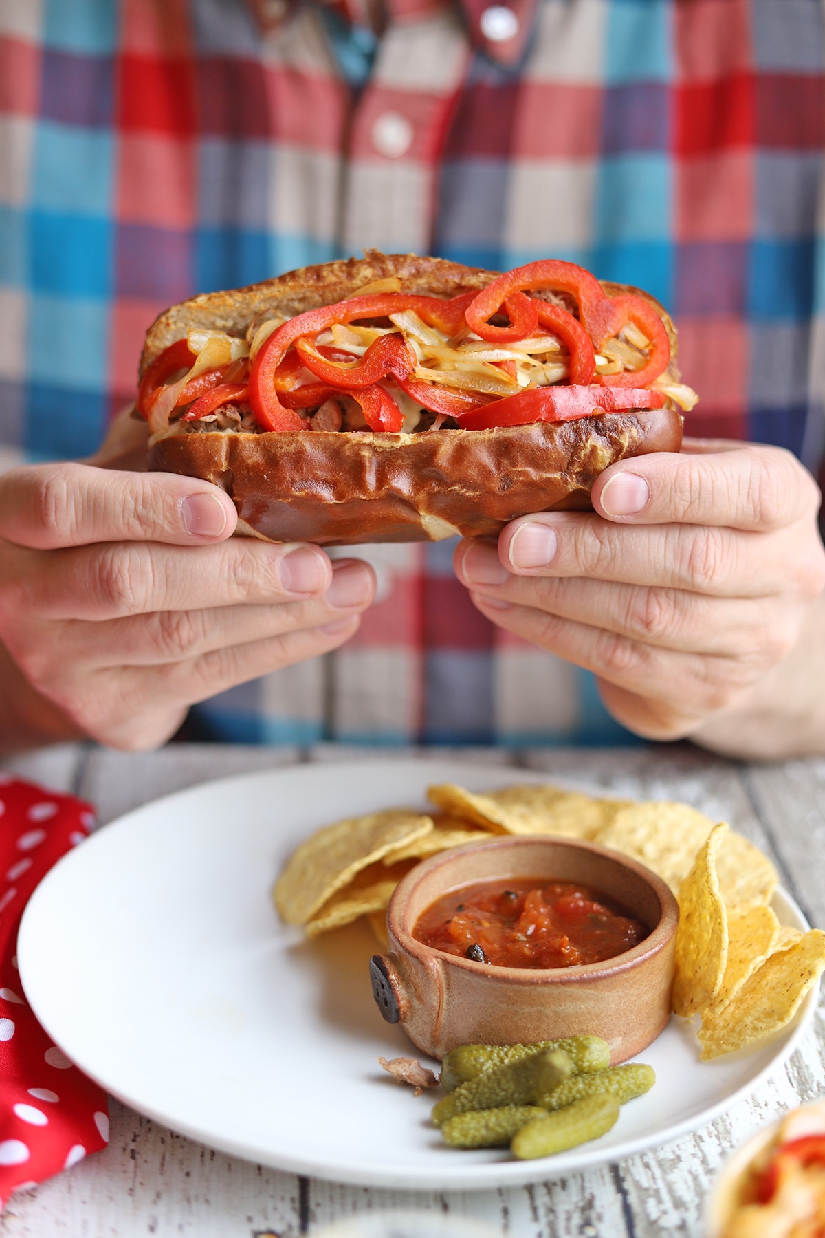 Hands holding vegan steak and cheese sandwich.