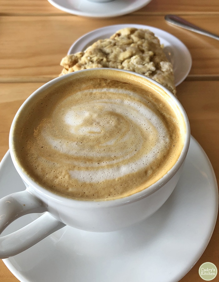 Almond milk latte and vegan scone on table.