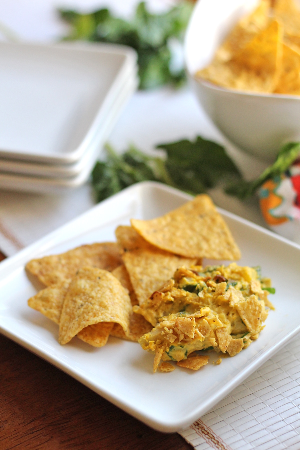 Vegan spinach artichoke dip on plate with tortilla chips.