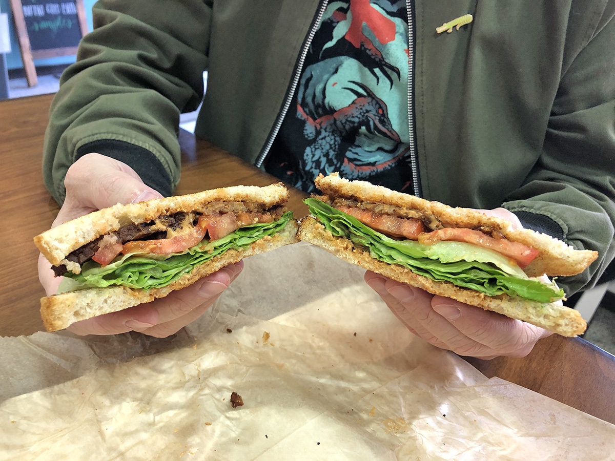 Hands holding tempeh BLT.