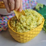 Tortilla chip dipping into pineapple salsa.