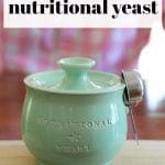 Text: 25 ways to use nutritional yeast. Jar of nutritional yeast on table.