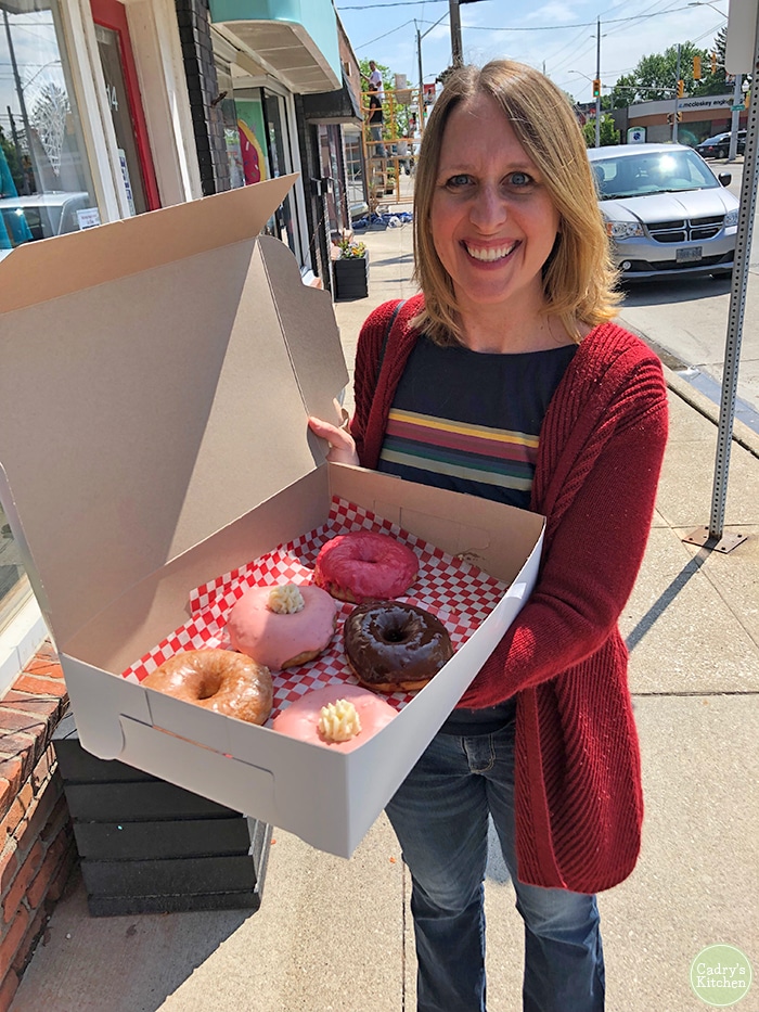 Cadry holding a box of vegan donuts in front of Plant Joy.