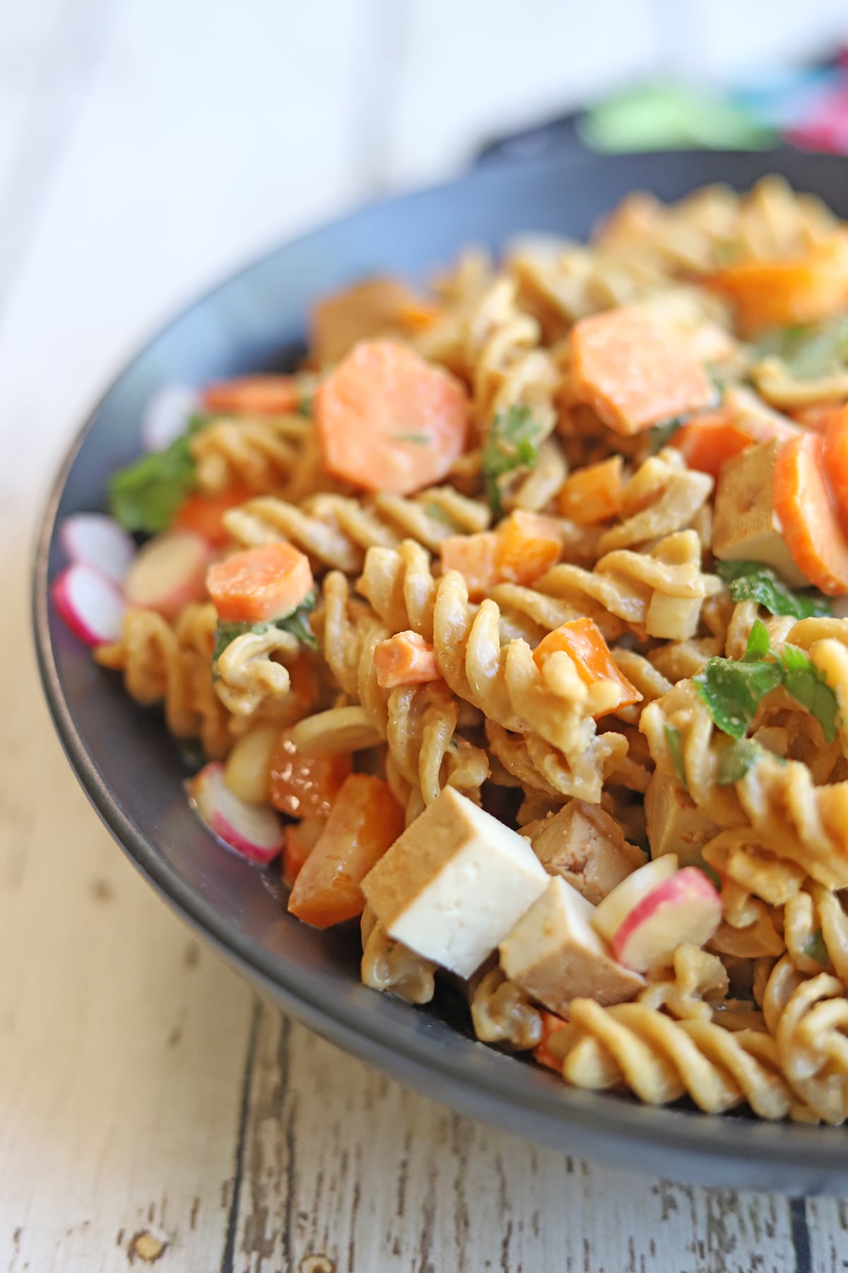Peanut noodles with vegetables and tofu in bowl.