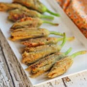 Vegan fried cashew cheese stuffed squash blossoms on platter.