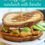 Text: Bulgogi tofu sandwich with kimchi. Sandwich on plate.
