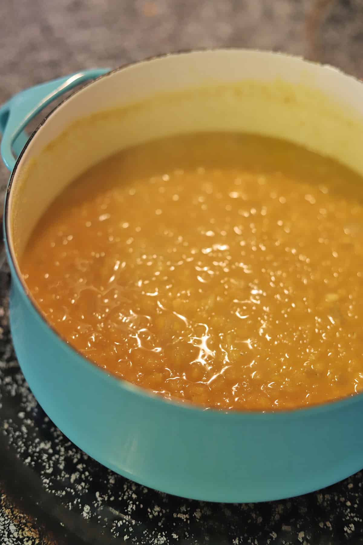 Red lentil soup on stove after lentils have disintegrated.