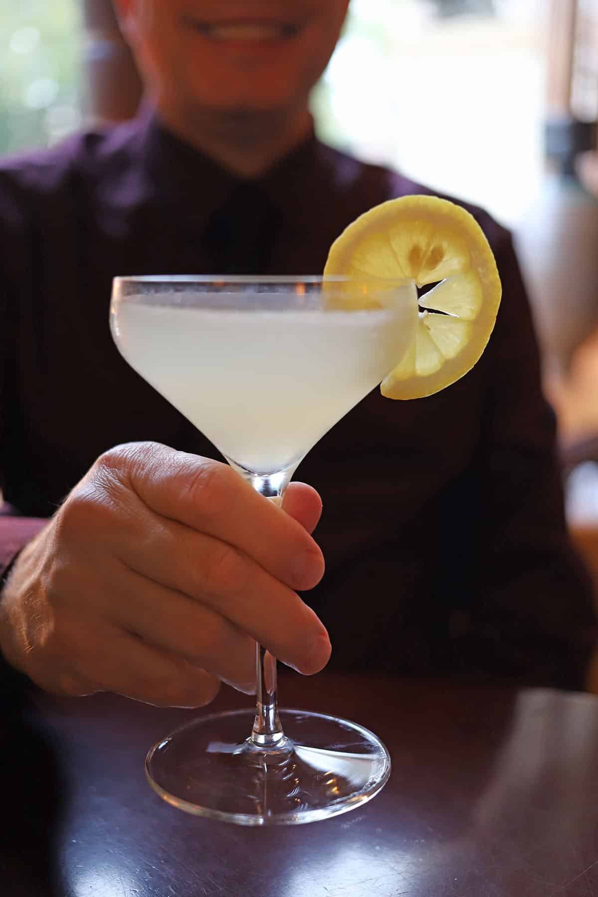 Hand holding lemon cocktail.